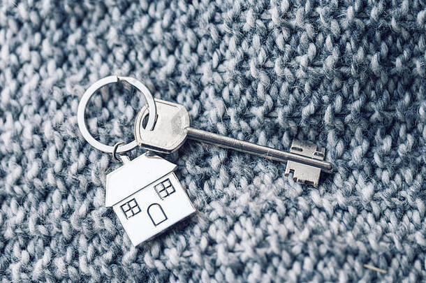 房屋钥匙和钥匙链以房屋的形式存在于针织羊毛织物上。房<strong>地产</strong>、抵押、搬家或物业的概念。