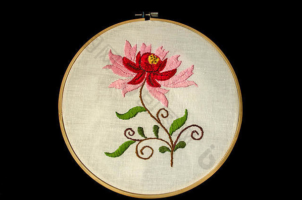 木质刺绣框架上的白色棉织物，扭曲的树枝上有红色和粉色花瓣的花朵，叶子背景为黑色