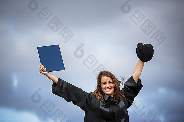美丽的年轻女子欢庆她的毕业典礼——张开双臂，拿着毕业证书，品味她的成功（c
