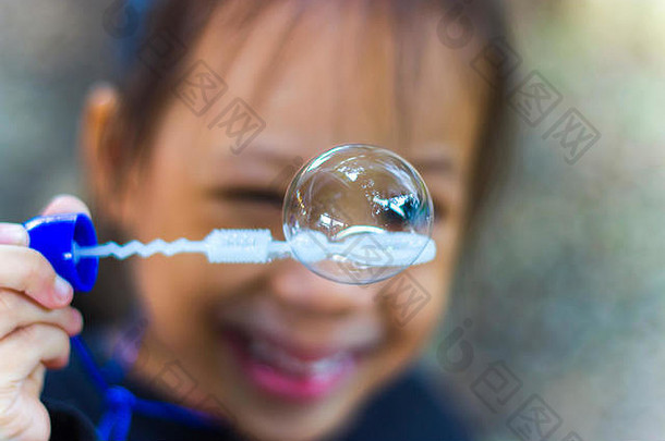 亚洲小男孩正在吹肥皂泡，户外画像