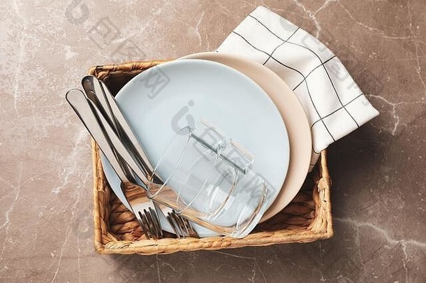 柳条篮，灰色背景，带盘子、杯子和叉子，俯视图