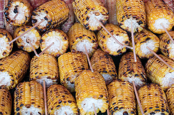 在泰国当地市场用木串烤甜玉米。