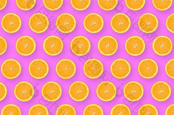 亮紫色背景上橙色水果片的俯视图。饱和的柑橘图案。极简平铺