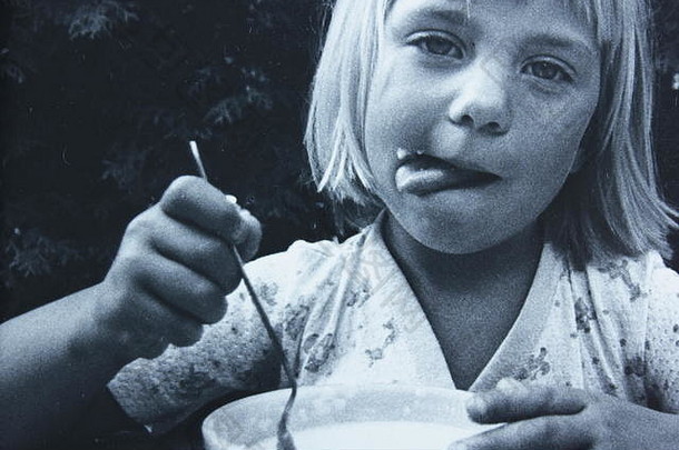 20世纪70年代拍摄的一个白人女孩吃一碗麦片的黑白艺术摄影。