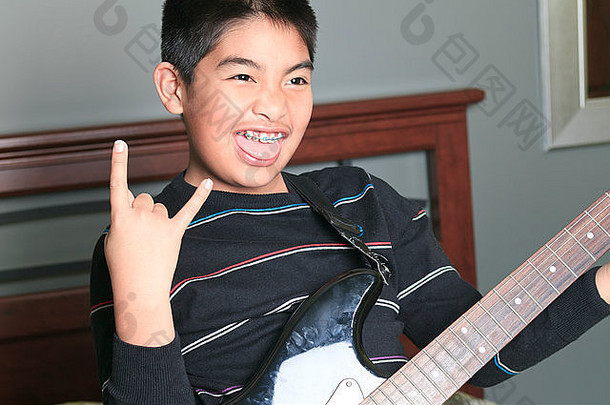 亚洲男孩玩吉他卧室