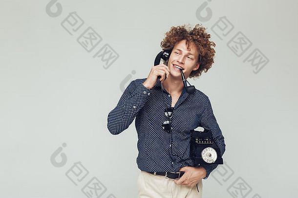 图片年轻的英俊的复古的男人。穿着衬衫站摆姿势孤立的电话手