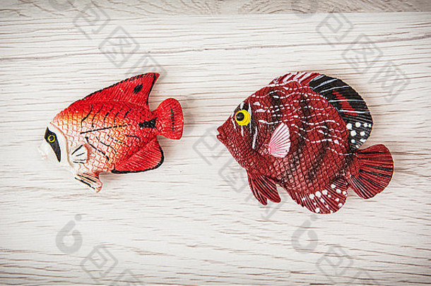 木制背景上的红色塑料鱼玩具。