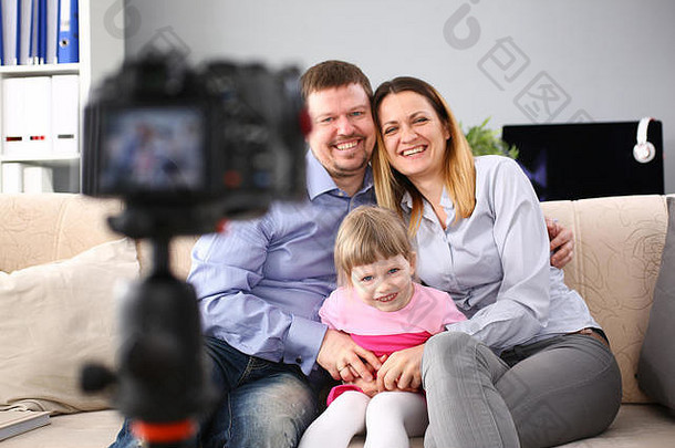 年轻的快乐家庭坐沙发上使照片会话肖像
