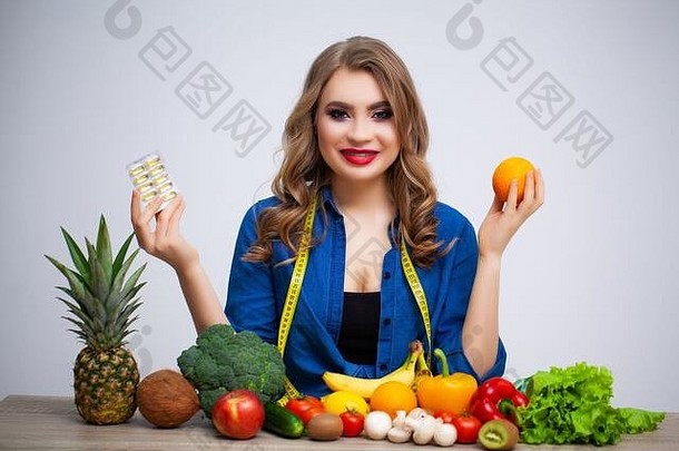 女人表格持有橙色药片水果蔬菜背景