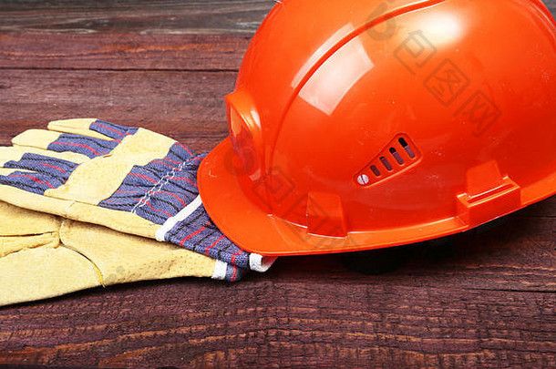 橙色安全帽和手套，用于在木质背景上工作。