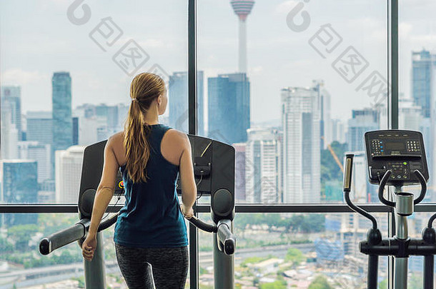 运动、健身、生活方式、技术和人的概念——在大城市背景下，女人在健身房的跑步机上锻炼