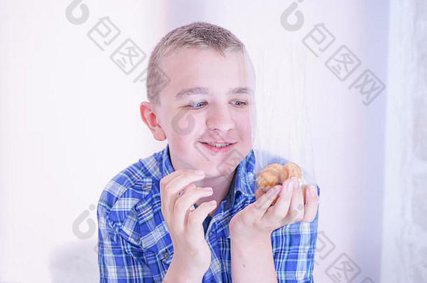 可爱的饥饿少年，在白色房间背景上独自拿着新鲜的小烤糖果