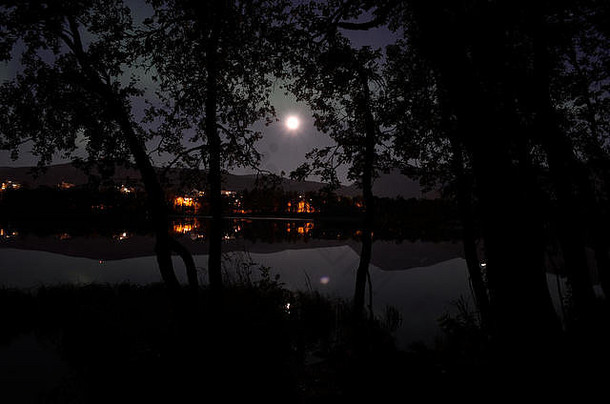 壮丽的北极光，夜晚平静的镜湖上的北极光，背景是建筑物