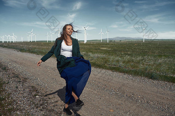 一个头发蓬乱的女人站在风机旁随风飘动