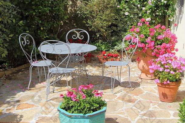 夏季，花盆中有天竺葵和灰色金属花园家具的带花露台