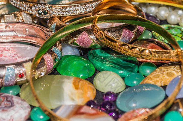 一堆珠宝、金手镯、珍珠项链和彩色宝石。财富与投资背景