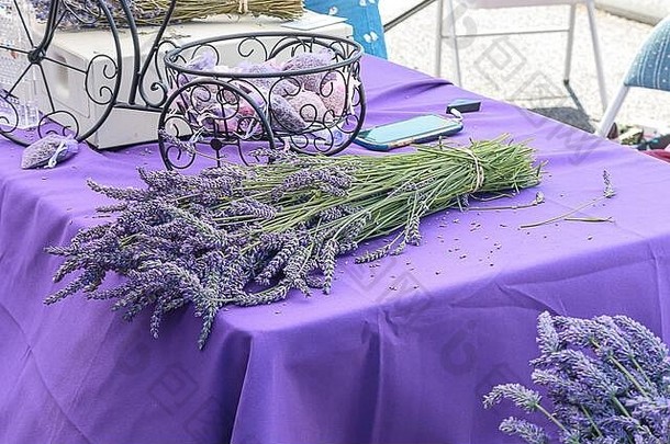 一束非常芳香的紫色薰衣草，放在紫色的桌面上，上面有香囊