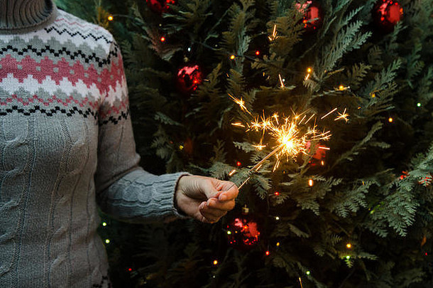 女人针织毛衣持有罗马焰火筒圣诞节树