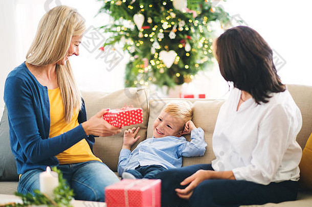 圣诞节时，一位母亲和祖母在家里给一个小男孩送礼物。