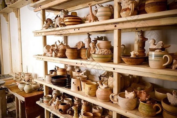 陶器车间的木架上摆放着陶器，许多不同的陶器摆放在陶器车间的架子上。微光