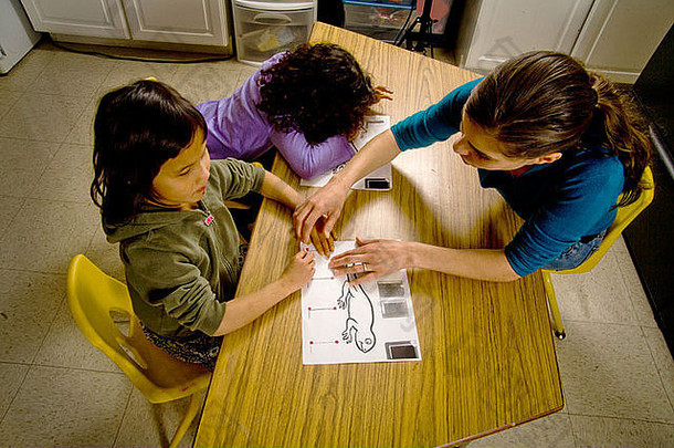 在特殊需要写作课上，一位老师引导一个盲童的手画出一只凸起的蜥蜴的轮廓。