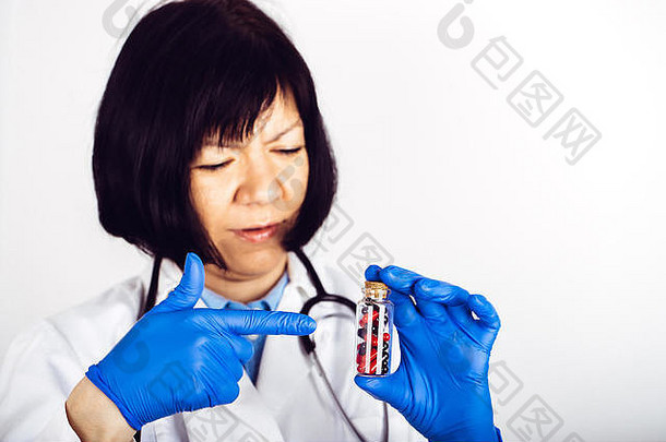 女医生白色实验室外套医疗手套持有玻璃瓶暗红胶囊图像