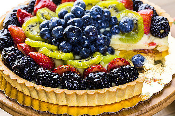 新鲜水果馅饼放在木桌上的蛋糕架上。