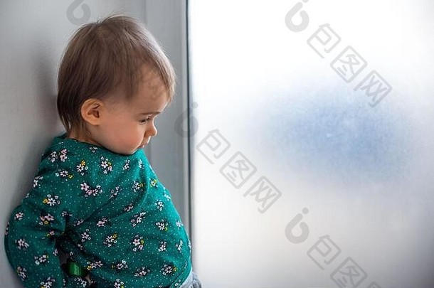可爱的高加索人一年婴儿女孩绿色衬衫站回来墙明亮的窗口