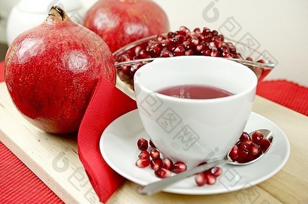 石榴茶，水果和石榴籽在木板上。白杯健康石榴茶。食物和饮料图片