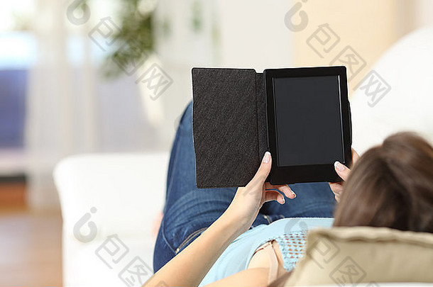 一个女孩在家里的沙发上看电子书，屏幕上是空白的