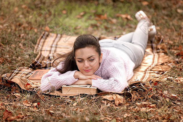 坐在秋天公园里看书的女人