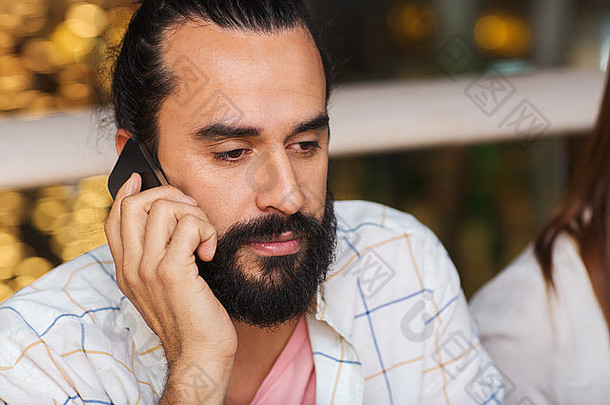悲伤的男人在餐厅用智能手机打电话