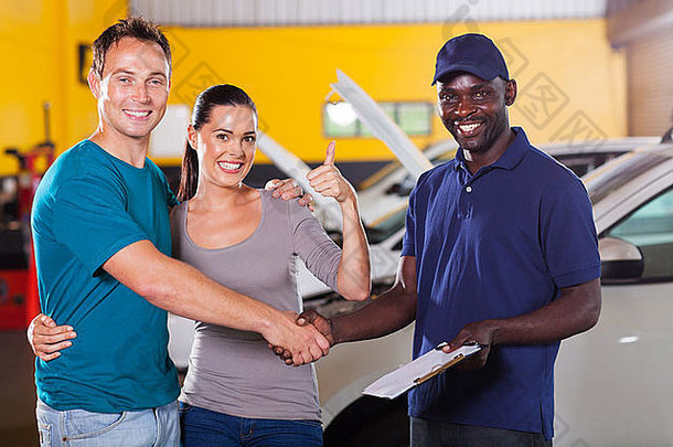 幸福的年轻夫妇向汽车修理店伸出大拇指