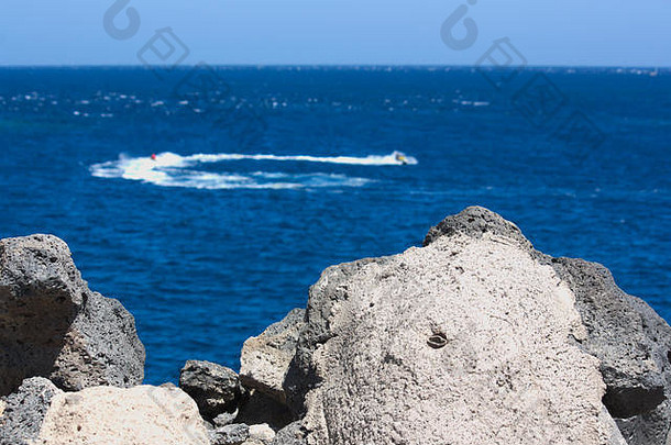 从海岸看到的水上摩托艇，在经过时形成泡沫轨迹并转弯