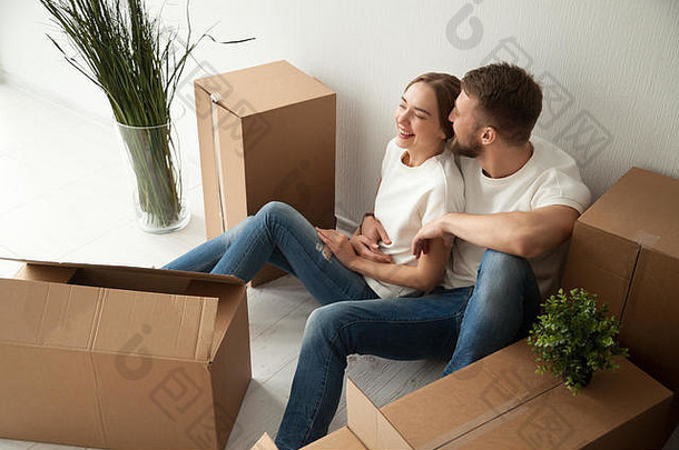 坐在新公寓地板上的一对欢笑的年轻夫妇
