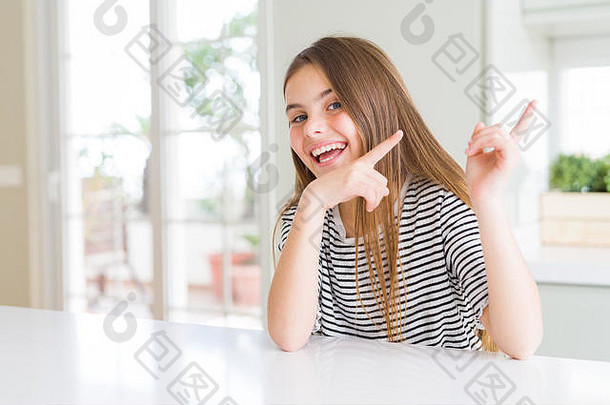 穿着条纹t恤的年轻漂亮女孩微笑着看着摄像机，双手和手指指向侧面。