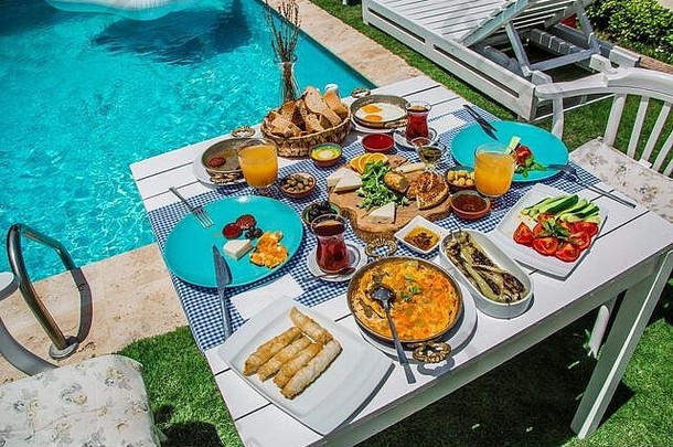 酒店概念促销早餐，美味的本笃鸡蛋，土耳其和法国早餐，茶和橙汁。游泳池附近