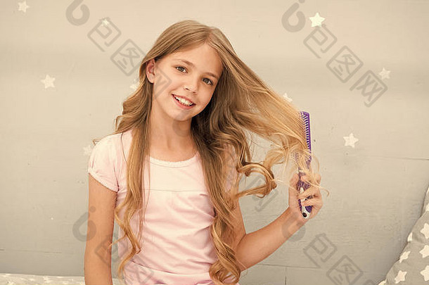 孩子卷曲的发型持有毛刷梳子梳子头发睡眠美容习惯概念护发素面具有机石油梳子头发女孩长卷曲的头发卧室室内背景