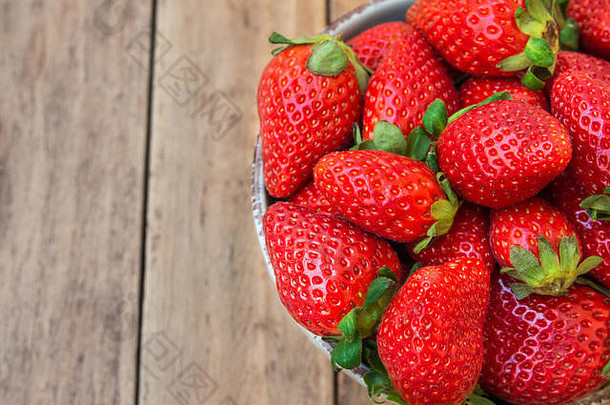成熟的有机草莓在木板木背景的蓝色陶瓷碗中，特写，健康食品，清洁概念，俯视图