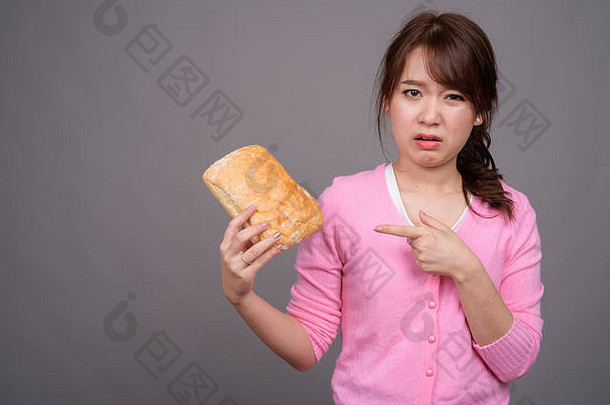 年轻漂亮的亚洲女人拿着一块面包