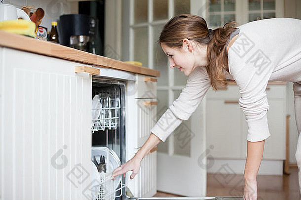 家务：年轻女子把盘子放进洗碗机