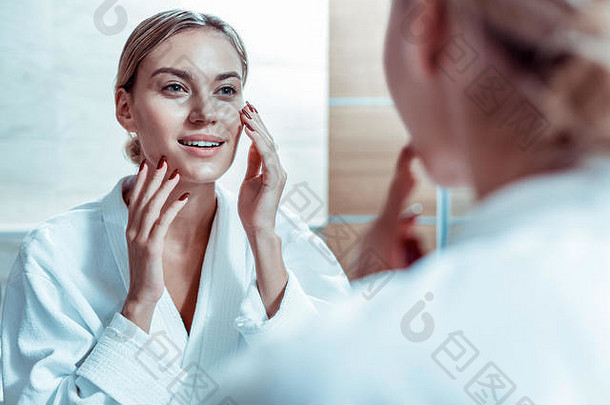 平静金发女郎女人触碰脸检查状态皮肤