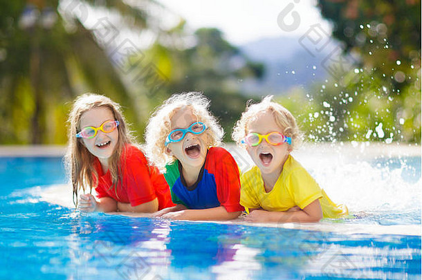 孩子们在游泳池里玩。家庭暑假期间，孩子们在热带度假胜地的室外游泳池里学习游泳。水和飞溅的乐趣，为年轻的基