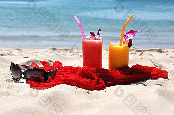 热带海滩上的水果奶昔、红色披肩和太阳镜