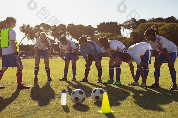 教练帮助女足球球员热身锻炼