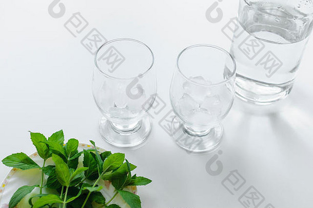 盘子上放两杯冰块、一瓶水和新鲜绿薄荷。