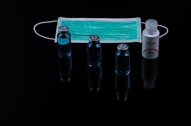 洗手液、疫苗和医用外科口罩，以防止黑暗背景下的冠状病毒等细菌。