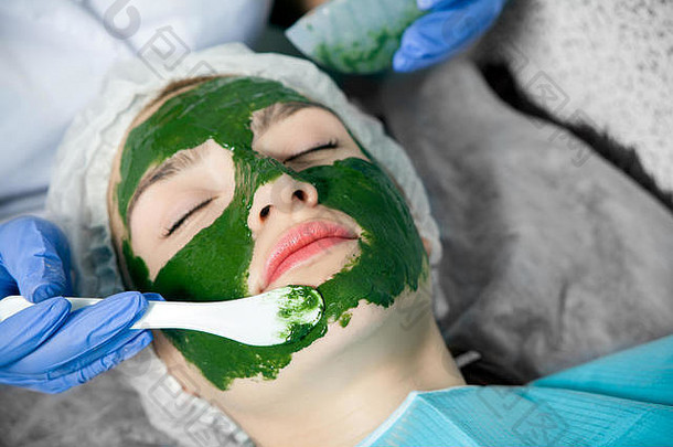 特写镜头美容师蓝色的手套特殊的化妆刷使治疗水疗中心面具绿色藻类老化年轻的red-h