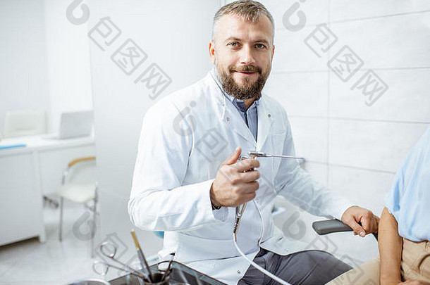 一位高级耳鼻喉科医生的肖像，穿着医用长袍，在手术室使用耳鼻喉科冲洗工具