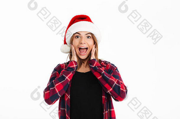 穿着衬衫、戴着圣诞帽的<strong>快</strong>乐的黑发女人尖叫着看着白色背景下的摄像机